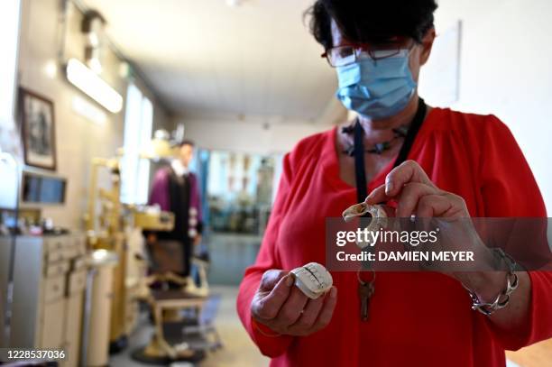 In this photograph taken on September 15 Annick Le Mescam, president of the Hospital heritage conservatory shows a dental prosthesis made of...