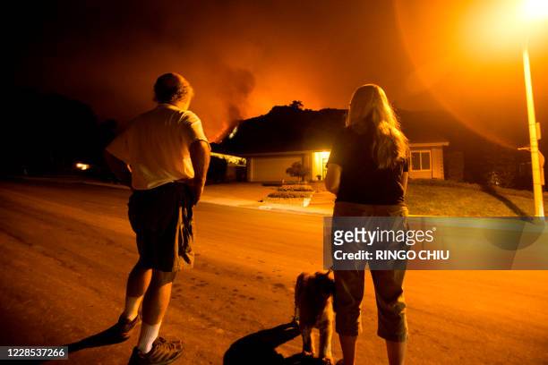 People watch as the Bobcat Fire burns on hillsides behind homes in Monrovia, California on September 15, 2020. - A major fire that has been raging...