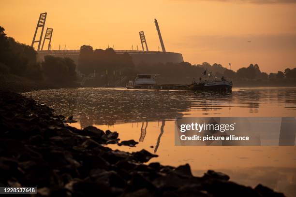 September 2020, Bremen: A ship passes the Weser Stadium in the early morning. The time of the ghost games is over in the Weserstadion for the time...