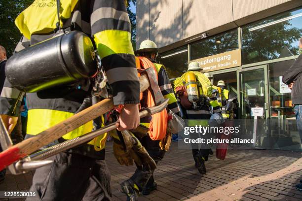 September 2020, Bavaria, Munich: Firefighters enter the court building of the Higher Regional Court II before the start of the trial against the...