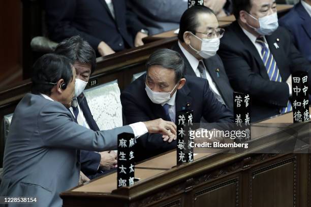 Yoshihide Suga, president of the Liberal Democratic Party , center, listens to Taro Aso, Japan's deputy prime minister and finance minister, left,...