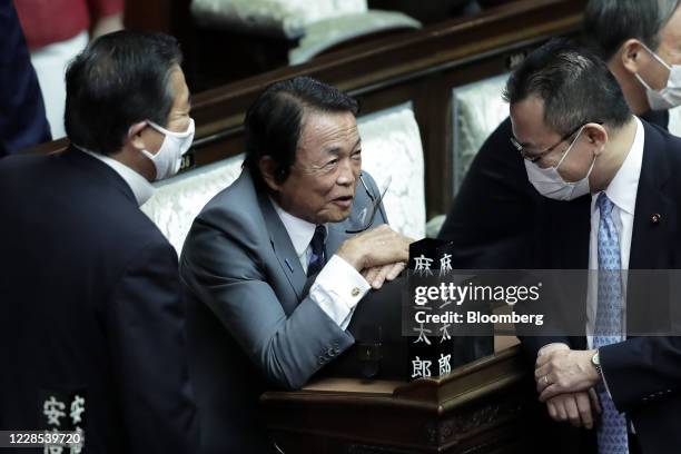 Taro Aso, Japan's deputy prime minister and finance minister, center, speaks to lawmakers before an extraordinary session at the lower house of...