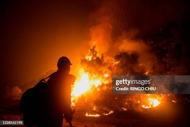 Firefighter watches the Bobcat Fire burning on hillsides near Monrovia Canyon Park in Monrovia, California on September 15, 2020. - A major fire that...