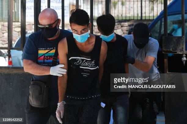 Migrants from Afghanistan escorted by police arrive at a court in Mytilene, the capital of the Greek Aegean island of Lesbos, on September 16 after...