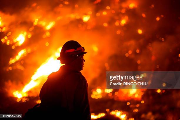 Firefighter watches the Bobcat Fire burning on hillsides near Monrovia Canyon Park in Monrovia, California on September 15, 2020. - A major fire that...