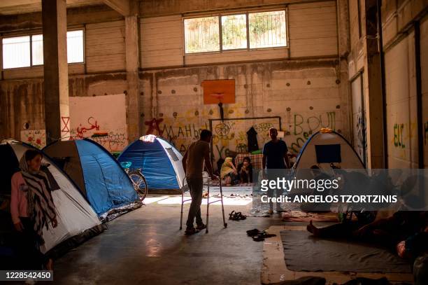 Migrants stand near tents in an abandoned building near the Kara Tepe camp, on the Greek Aegean island of Lesbos on September 16 after the Moria...