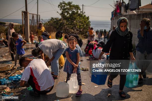Girl waits to fill bottles with water near a temporary migrant camp on the Greek Aegean island of Lesbos on September 16 after the Moria camp was...