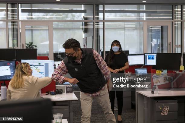 Employees wearing protective masks elbow bump at a JLL office in Menlo Park, California, U.S., on Tuesday, Sept. 15, 2020. Constraints such as social...