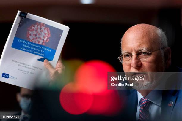 Centers for Disease Control and Prevention Director Dr. Robert Redfield holds up a CDC document while he speaks at a hearing of the Senate...