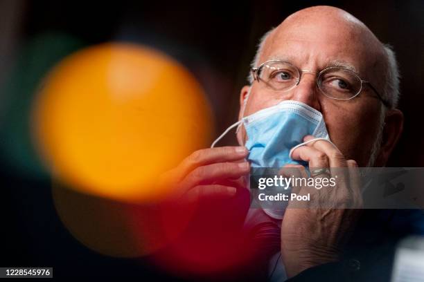 Centers for Disease Control and Prevention Director Dr. Robert Redfield puts his mask on after speaking at a hearing of the Senate Appropriations...