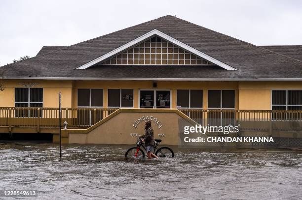 Man walks with his bicycle through a street flooded by rains from Hurricane Sally in downtown Pensacola, Florida on September 16, 2020. - Hurricane...