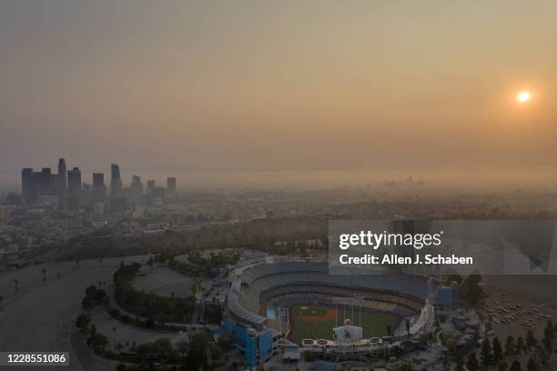 An aerial view of Dodger Stadium, downtown Los Angeles skyline and sunset is obscured by smoke, ash and smog Monday, Sept. 14, 2020 in Los Angeles....