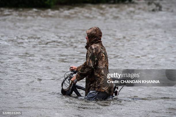Man walks his bicycle through a street flooded by Hurricane Sally in Pensacola, Florida, on September 16, 2020. - Hurricane Sally barrelled into the...