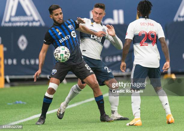 Jakob Nerwinski of the Vancouver Whitecaps tires to take the ball away from Saphir Taider of the Montreal Impact as Yordy Reyna looks on during MLS...