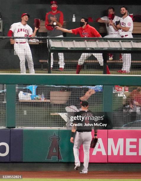 Josh Rojas of the Arizona Diamondbacks stands on the warning track while Los Angeles Angels players in the bullpen try to catch a home run ball hit...