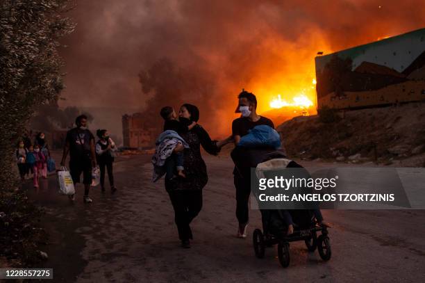 Family of migrants flee the Moria camp after a fire broke out, on the island of Lesbos on September 9, 2020. - Thousands of asylum seekers on the...