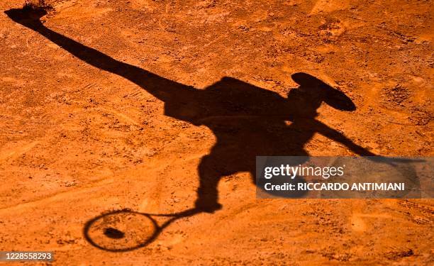 The shadow of USA's Cori Gauff is cast on the clay as she plays a forehand to Spain's Garbine Muguruza on day four of the Women's Italian Open at...