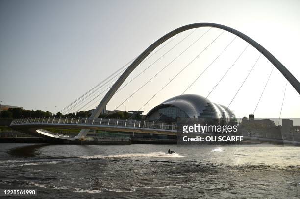 Man rides a jet ski under the Millennium Bridge on the River Tyne in the early evening sunshine in Newcastle upon Tyne, north-east England, on...