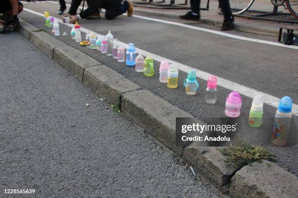 Mothers, with children under the age of 6, hang nursing bottles in front of the government headquarters to express that there is no one to take care...