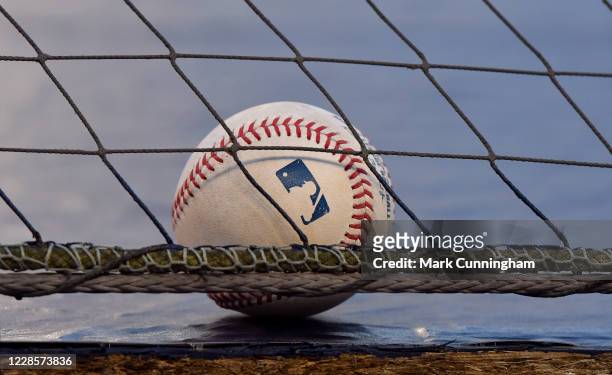 Detailed view of a Rawlings official Major League Baseball sitting on top of the dugout behind the protective netting during the game between the...