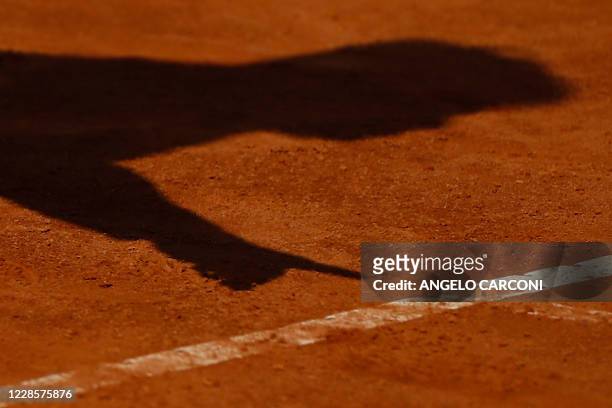 The shadow of the umpire showing a ball mark is cast on the clay during the round 3 match between Britain's Johanna Konta and Spain's Garbine...
