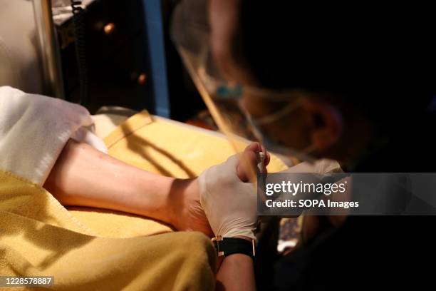 Staff member wearing a face mask is seen massaging a man at a beauty spa. Government officials said that they should further relax social-distancing...