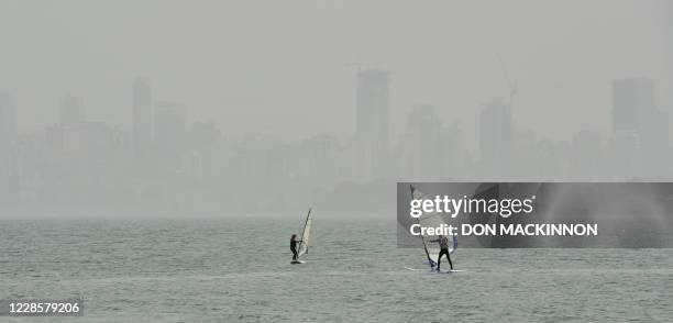 People windsurf in Burrard inlet as the heavy smog and smell of wood smoke hangs over the Vancouver, British Columbia skyline in the background on...