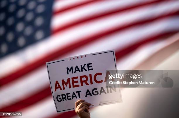 Man waves a "Make America Great Again" sign before President Donald Trump arrives for a rally at the Bemidji Regional Airport on September 18, 2020...