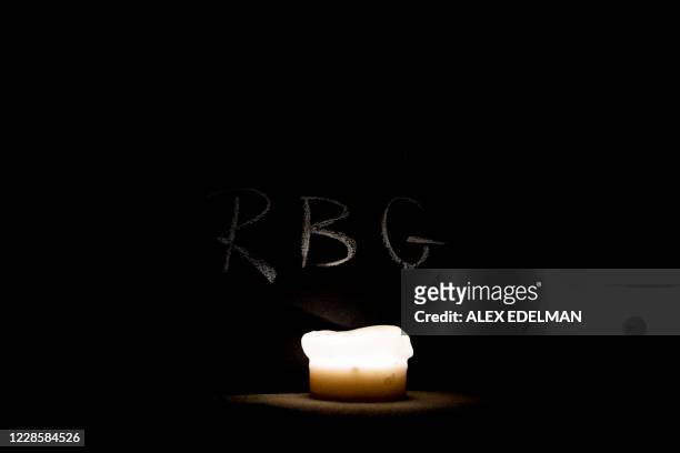 Is written above a lit candle as mourners gather on the steps of the Supreme Court after the passing of US Supreme Court Justice Ruth Bader Ginsburg,...