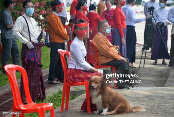 Myanmar's de-facto leader Aung San Suu Kyi wearing a facemask and gloves, to halt the spread of the COVID-19 coronavirus, waits with her dog to wave...