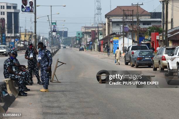 Police officers sit on fences next to a blocked road during the Edo State governorship elections in Benin City, Midwestern Nigeria, on September 19,...