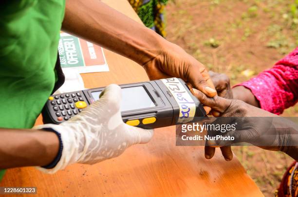 Woman puts his thumbprint on a fingerprint scanner to vote in the during the governorship election in Benin City, Edo State. As voters gathered to...