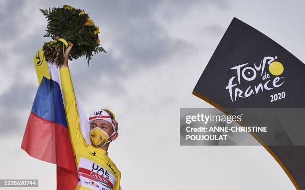 Team UAE Emirates rider Slovenia's Tadej Pogacar wearing the overall leader's yellow jersey celebrates on the podium after winning the 107th edition...