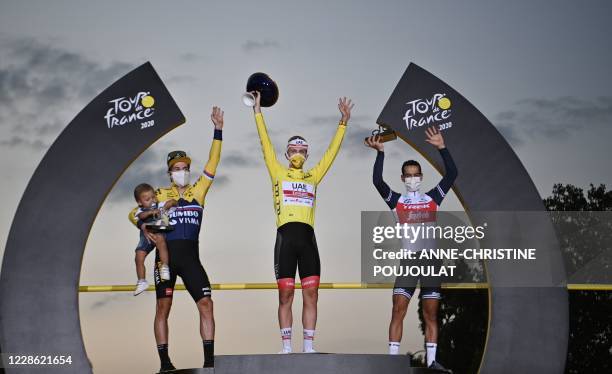 Team UAE Emirates rider Slovenia's Tadej Pogacar wearing the overall leader's yellow jersey celebrates on the podium between Team Jumbo rider...