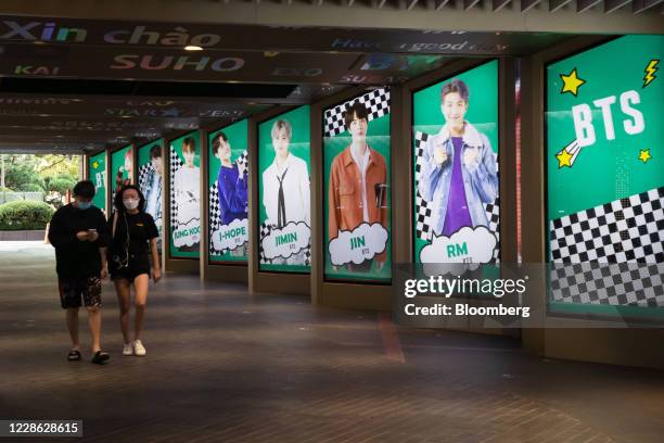 Pedestrians wearing protective masks walk past an advertisement for K-pop boy band BTS displayed in Seoul, South Korea, on Friday, Sept. 18. 2020....