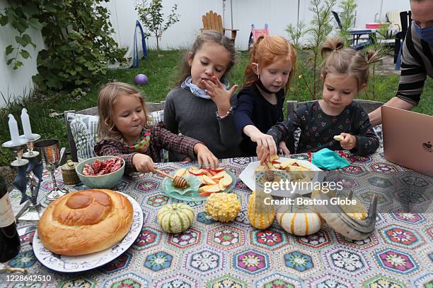 Young girls eat apples and honey in Newton, MA on Sept. 18, 2020 for Rosh Hashanah before participating in the Jewish New Year Services with Temple...