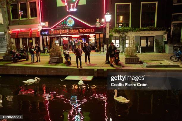 People look to swans on a canal in the Red Light District on September 21, 2020 in Amsterdam, Netherlands. Due to the rapid rise in new Coronavirus...