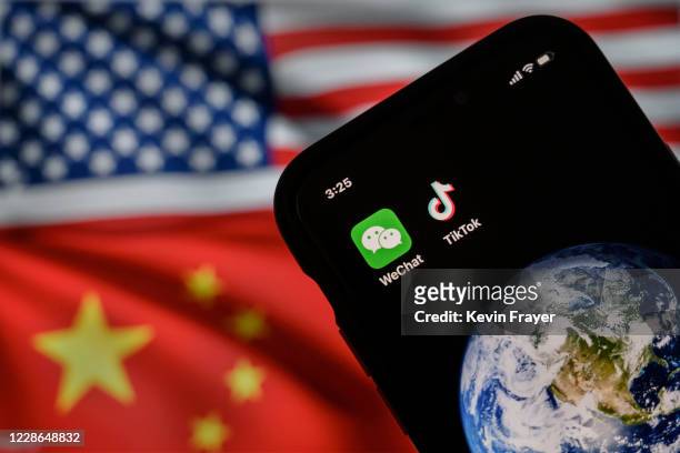 In this photo illustration, a mobile phone can be seen displaying the logos for Chinese apps WeChat and TikTok in front of a monitor showing the...