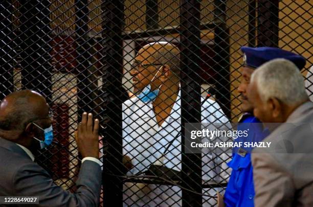 Sudan's ousted president Omar al-Bashir stands inside the defendant's cage during his trial along with 27 co-accused, over the 1989 military coup...