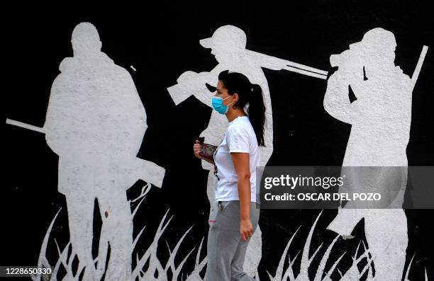 Woman wearing a facesmask walks past a mural in the under partial lockdown town of Fuenlabrada, in Madrid region, on September 22, 2020. - The...