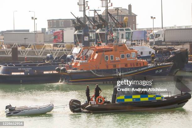 Police officers on a police boat tow two small inflatable dinghies into Dover after migrants were rescued by the RNLI. Migrants arrived into Dover...