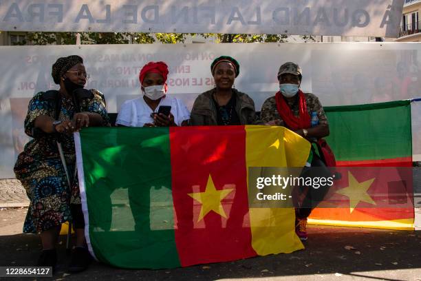 Cameroonian activists sit behind a national flag during a demonstration against Cameroon's President Paul Biya, near the embassy of Cameroon in Paris...