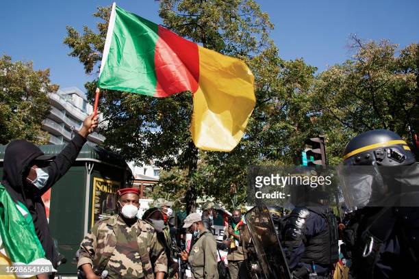An opponent of current Cameroonian president waves a national flag in front of French riot policemen during a demonstration against Cameroon's...