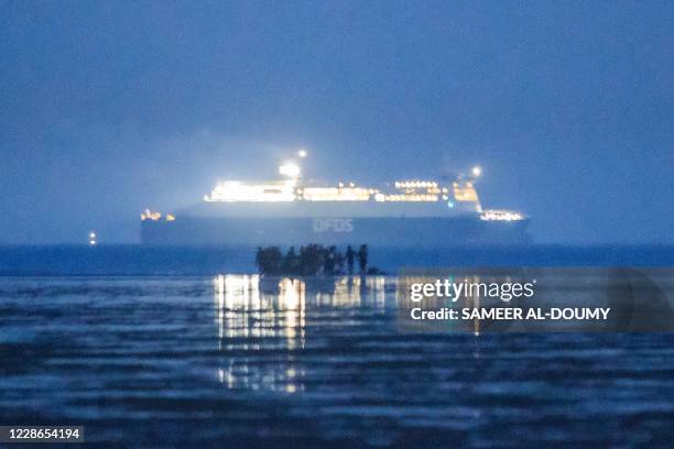 Migrants including families embark on the beach of Gravelines as a ferry of the Danish shipping company DFDS sails in the Channel , near Dunkirk,...