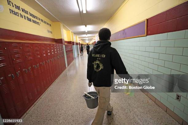 Earnest Bass, a custodian at McCormack Middle School in Dorchester, walks down the hallway with bucket in hand as he finished cleaning a nurses...