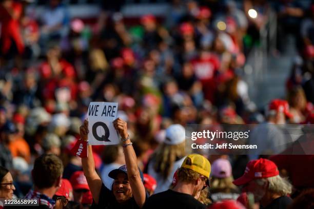 Woman holds up a QAnon sign to the media as attendees wait for President Donald Trump to speak at a campaign rally at Atlantic Aviation on September...