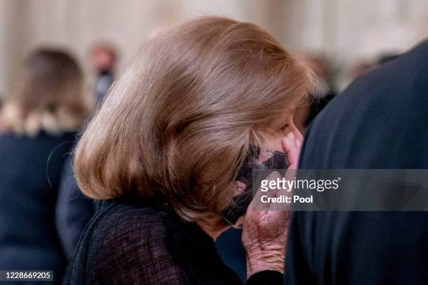 Supreme Court reporter Nina Totenberg wears a face mask with depictions of Justice Ruth Bader Ginsburg on it as she wipes her eye while the...
