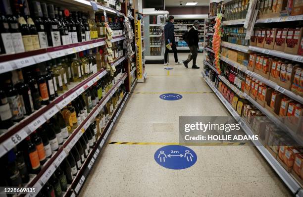 Floor stickers in the alcohol aisle inside a Tesco Metro supermarket ask customers to social distance as they shop, in London on September 23, 2020....