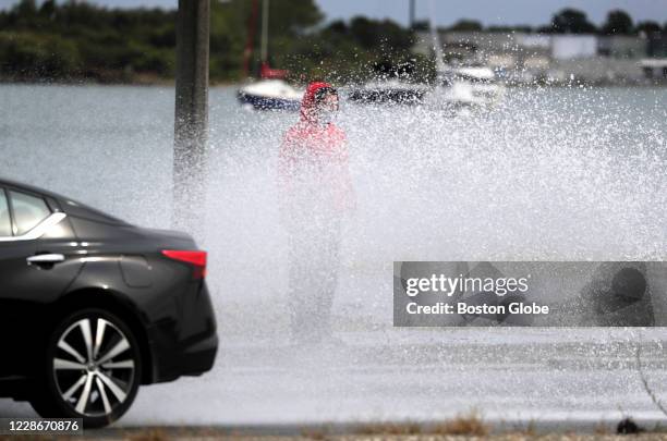 Passerby is hit by spray from vehicles during high tide flooding along Morrissey Boulevard in Boston's Dorchester on Sept. 22, 2020 as Hurricane...