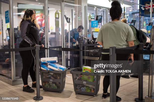 Shoppers queue for self-checkout tills with baskets full of toilet paper at Lidl supermarket in Walthamstow, east London on September 23, 2020. -...
